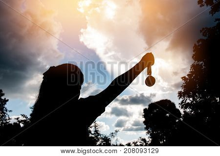 Blurred of silhouette hands raised and holding gold medals with ribbon against sunset background. to show team success in business Winners success award concept.