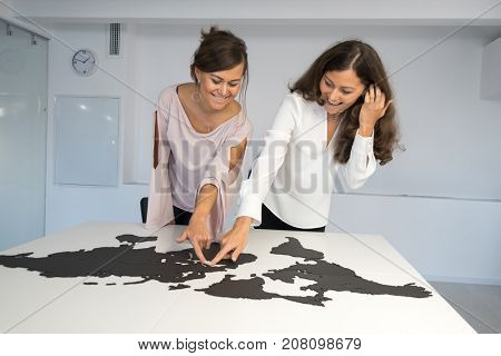 Twins girls fixing the world map on the table