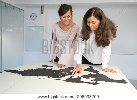 Twins girls fixing the world map on the table