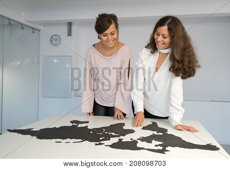 Twins girls fixing the world map on the table