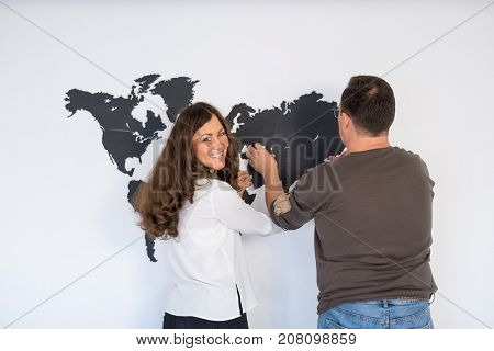 Couple is fixing the world map on the wall