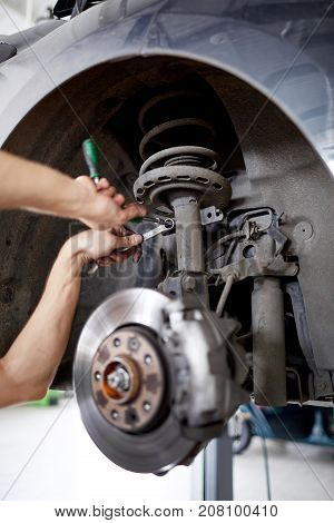 An unidentified mechanic repairing brake pads using tools from a green box