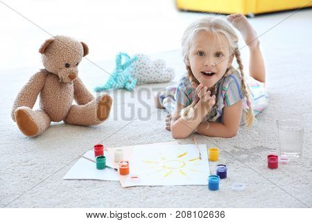 Cute little girl painting picture and spilled water on carpet