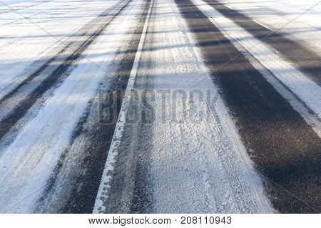 Road Covered With Snow In The Winter Season. On The Asphalt, You Can See The Ruts Of Snow