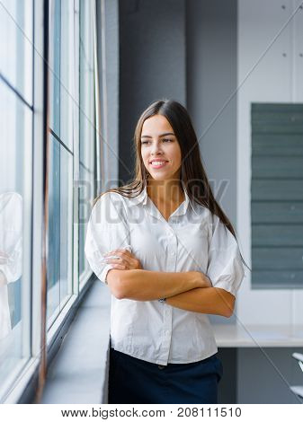 Portrait of attractive business woman posing on a blurred office background. Confident manager girl in stylish formal wear. Copy space.