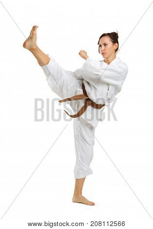 A girl in white uniform for karate with a brown belt on an isolated white background executes kicks with legs