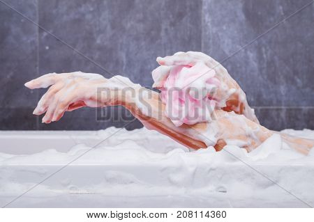 Close Up Of Woman Washing Arm With Sponge In Bathtub In The Bathroom