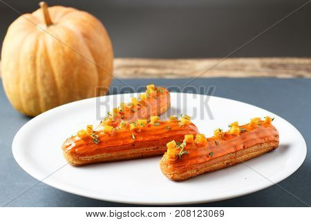 pumpkin orange eclairs on a white plate and pumpkin
