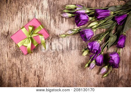 Pink gift box and eustoma. Romantic concept. Delicate flowers on a wooden background.