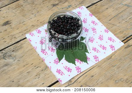 Ripe elderberry fruits in a glass jar