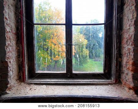 View of the autumn park through an old dirty window in abandoned palace in Belarus (Zheludok, Grodno region), built in the early twentieth century, example of Art Nouveau style