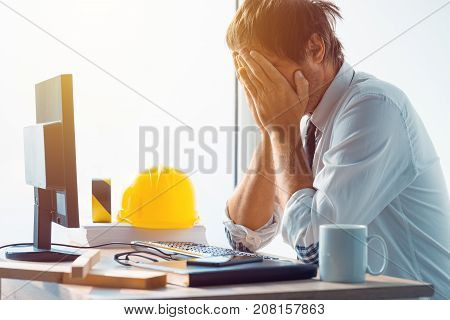 Architect and construction engineer having problems at work in office construction engineer working with computer and sketches on a construction project selective focus