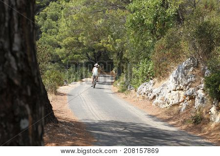 Woman biker on winding road through the woods. Croatia.