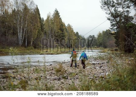 Tourists walking along the river Bank in autumn day