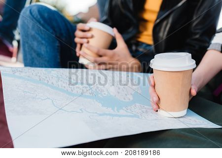 selective focus of women with map and coffee to go