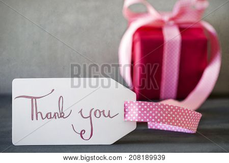 Label With English Calligraphy Thank You. Pink Gift Or Present With Gray Cement Background