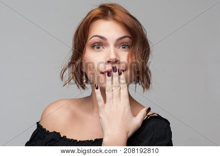 Female secrets. Flirty confusion young woman. Surprising news, shocked facial expression. Playful girl portrait on grey background, gossip concept