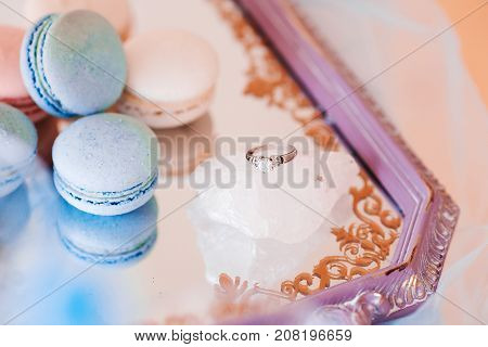 macarons with wedding ring on piece of crystal, on vintage tray close up shot