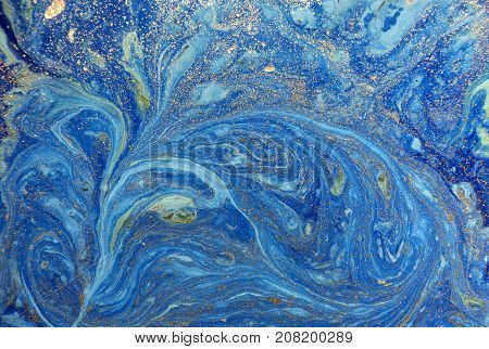 Marbled blue abstract background with golden sequins. Liquid marble ink pattern
