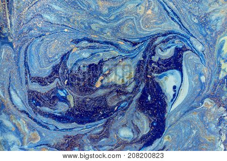 Marbled blue abstract background with golden sequins. Liquid marble ink pattern