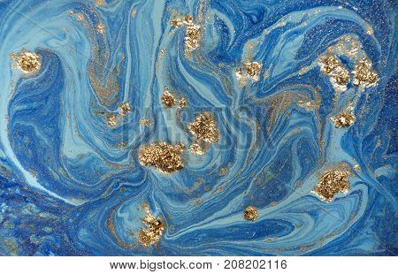 Marbled blue abstract background with golden sequins. Liquid marble ink pattern