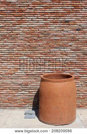 huge clay pot near old brik wall