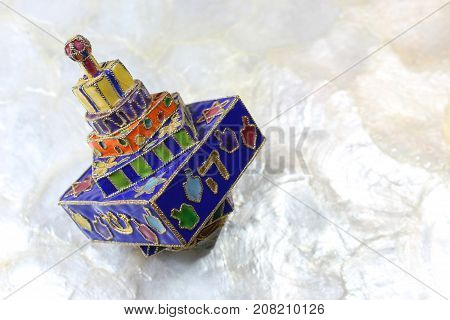 Festive colorful enameled Hanukkah dreidel on a soft white background