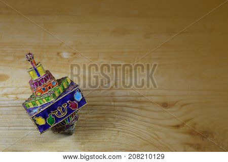 Bright and colorful enameled metal Hanukkah dreidel on a wood table