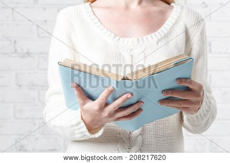 Blond woman reading book holdinh in hand