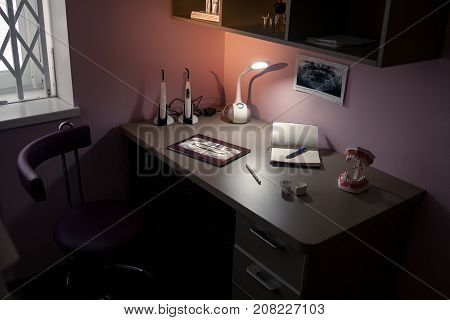 Work desk doctor with lamp notepad tablet computer and waxwork teeth in dental office.