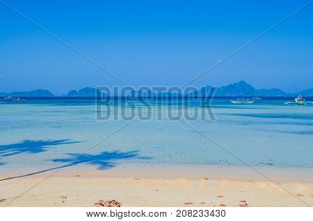 Corong corong beach. Seascape with island in ocean. Palm Shadows on the beach. El Nido, Palawan, Philippines.