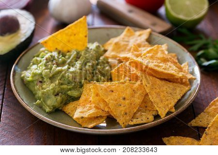 Plate of guacamole with tortilla chips and ingredients. Close up shot