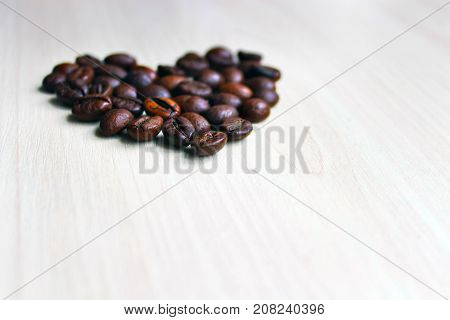 Heart laid out in the form of heart from coffee beans. Beige and brown colors predominate.