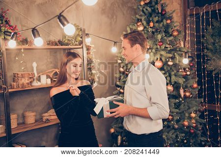 Sweet brown haired husband and cute wife are receiving green gift with white ribbon so excited cheerful elegant traditional decorations x mas enjoy winter december festive magic noel time!
