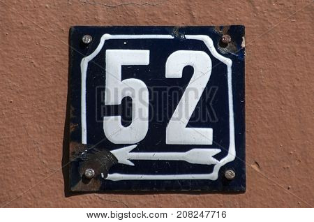 Weathered grunge square metal enameled plate of number of street address with number 52 closeup
