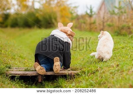 Cute funny little girl walking with her cat best friends kid and pet having fun together outdoors beautiful fall day childhood and friendship.