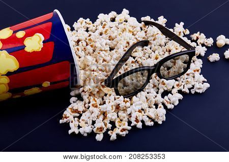 Bowl with scattered popcorn and 3D glasses on a wooden background