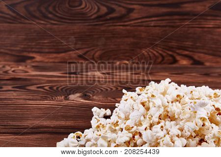 Spilled on the edges of popcorn on a wooden brown background which is sold in the cinema