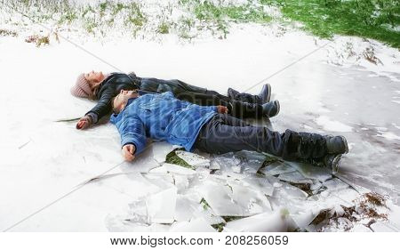 Happy cheerful young couple guy and girl lying on the ice snow. Having fun in winter holiday. Selective focus.