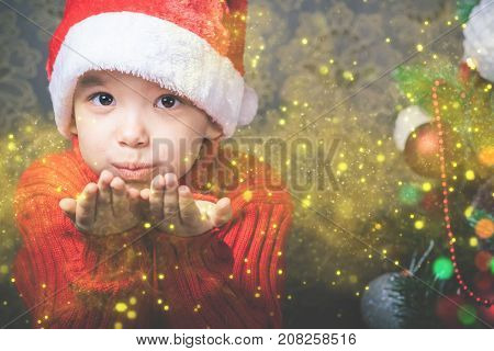 Little boy fairy blowing fairy magical glitter, stardust at Christmas. Christmas tree. Xmas child and New Year holiday. Merry Cristmas your family