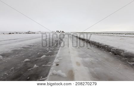 Ruts On The Road From Cars. The Roadway Is Covered With Snow In The Winter Season. Gray Sky In The B