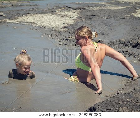 Mother gently bathing my daughter in the mud. Treatment non-traditional methods.