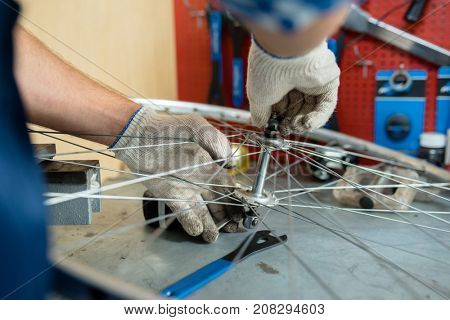 Repairman fixing bolt in the center of bicycle wheel