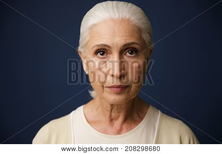 Close-up portrait of beautiful old woman, over dark blue background