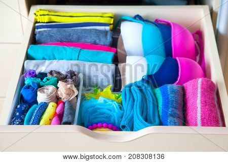 Neatly Folded Clothes With Accessories In Chest Of Drawers