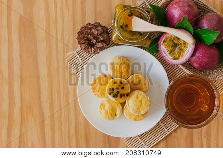 Homemade plain scones with passion fruit jam and tea. Scones is English pastry for afternoon tea or coffee break. Delicious scones served with passion fruit jam in top view flat lay with copy space. Scones and jam ready to served with tea.
