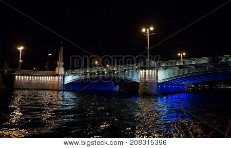 Night cityscape with river and bridge in Saint-Petersburg . Lantern lights on the bridge .