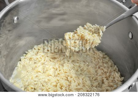 Spoon with boiled rice above stewpot