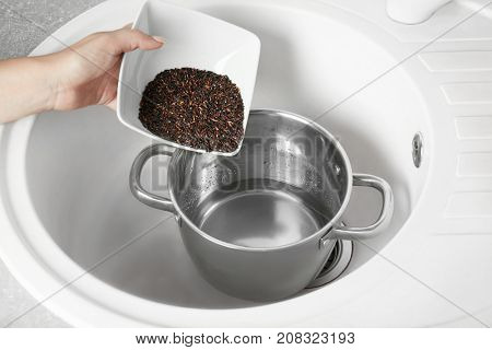 Woman pouring brown rice into stewpot
