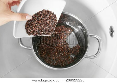 Woman pouring brown rice into stewpot